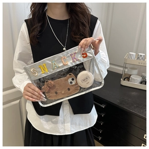 Detailed view of clear PVC makeup bag with SNACKS patch and silver leather piping
