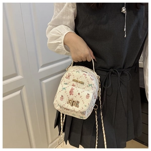 Detail of white mini backpack with cartoon patterns, gold chain, and fashion metal lock