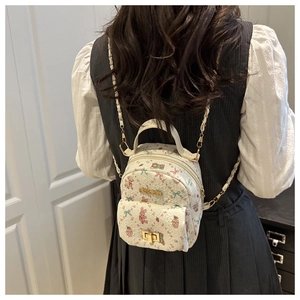 Mini backpack featuring cute floral cartoon patterns and gold chain straps on a model back