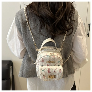 Close-up of mini backpack with pink bear prints and gold chain straps on a model