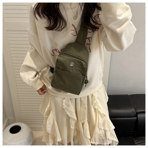 Close-up of olive green waterproof nylon crossbody bag with metallic M emblem on model