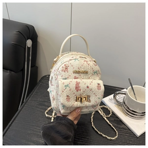 Close-up of white mini backpack with floral prints, golden chain, and FASHION metal logo