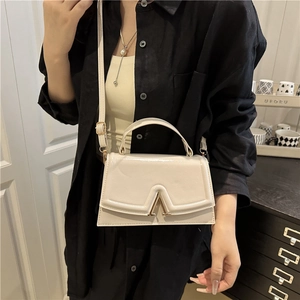 Minimalist cream white crossbody bag with polished finish and stylish metal V-shaped clasp