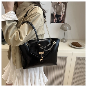 Close-up of black glossy PU tote bag featuring gold chain and deer charm pendant
