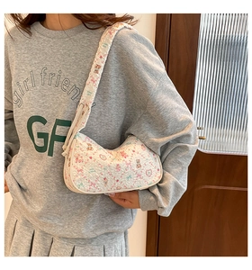 Close-up of a white shoulder bag with colorful cartoon bear and floral print patterns