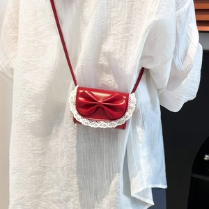 Mini red crossbody bag with 3D bow and lace trim shown on white shirt model