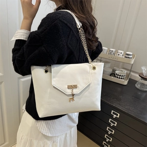 White leather tote bag with gold chain strap and deer pendant on minimalist shoulder bag