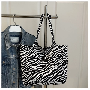 Detail of zebra stripe canvas tote bag featuring a front pocket and stylish fashion label