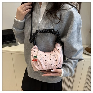 Detail of pink pleated handbag with black ruched handle and red cherry charm accessory