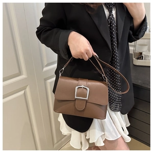 Brown leather shoulder bag with a large silver metal buckle shown on a model