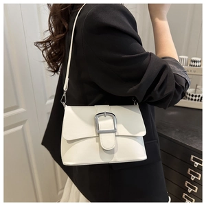 Detailed view of the silver metal buckle on the white leather crossbody bag worn by a model