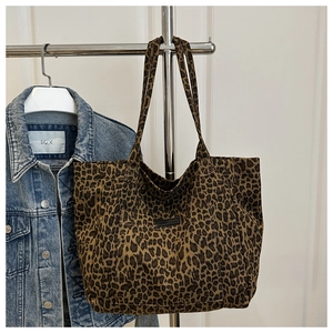Detail of leopard print canvas tote bag with front pocket hung beside denim jacket