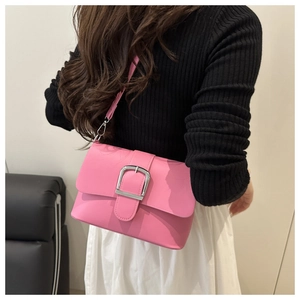 Detail of hot pink patent leather shoulder bag featuring a large silver buckle