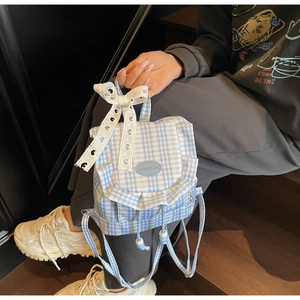 Detail of blue plaid mini backpack featuring white lace bow and ruffled edges decoration