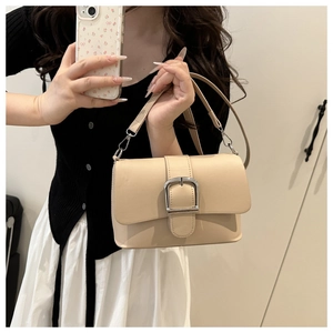 Detail of apricot shoulder bag featuring a silver horseshoe buckle and smooth leather finish