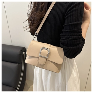 Detail of beige flap shoulder bag with a large silver metal buckle on a chic model