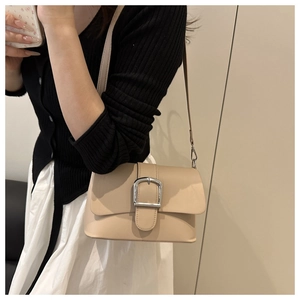 Close-up of beige leather crossbody bag with large square silver metal buckle and strap