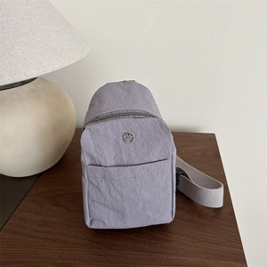 Gray nylon outdoor crossbody bag with silver logo on wooden table minimalist setting