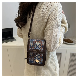 Close-up of retro geometric patterned crossbody bag with gold round hardware detail