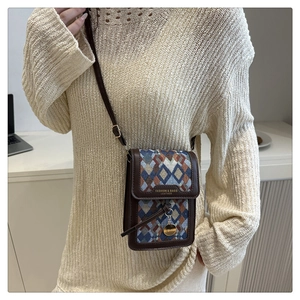Detail of vintage crossbody bag with geometric patterns and leather trim on model