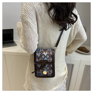 Detailed view of jacquard geometric crossbody bag with gold pendant and leather trim