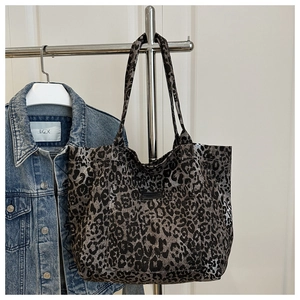 Detailed close-up of leopard print tote bag with front pocket hanging on a hanger