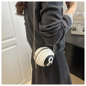 White billiard 8-ball shaped cross-body bag with gold chain strap worn by a model