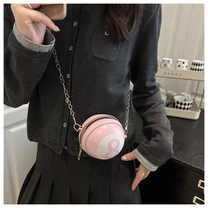 Close-up of pink billiards 8-ball mini crossbody bag with gold chain strap on model