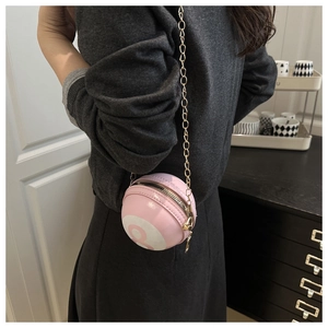 Detailed close-up of a pink sphere crossbody bag with gold chain and pool ball design