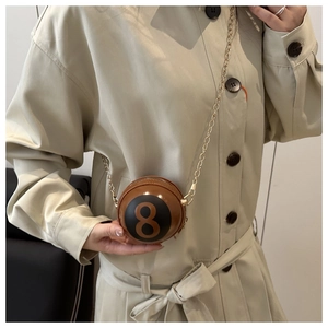 Detail of unique 8-ball spherical crossbody bag with gold chain strap on model