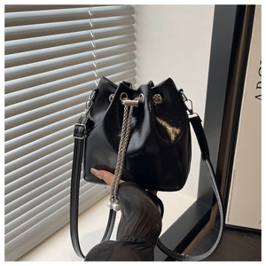 Detail of black glossy bucket bag with silver chain drawstring and pearl charms