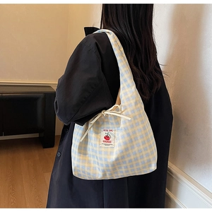 Dettaglio della borsa tote a quadri blu e gialli con coulisse e toppa con logo pomodoro