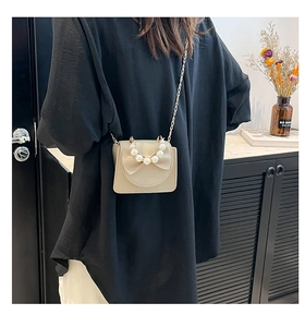 Detail of beige crossbody bag with bow decoration and elegant large pearl handle