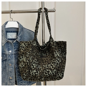 Close-up of leopard print canvas tote bag hanging on a rack with a denim jacket