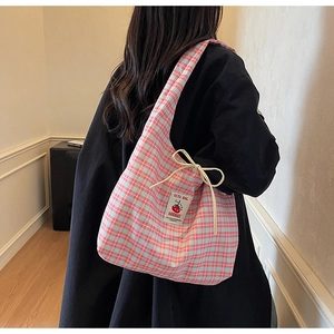 Dettaglio della borsa tote a quadri rosa e blu con etichetta pomodoro e lacci decorativi
