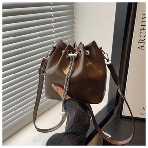 Macro shot of dark brown bucket bag with silver chain drawstring and pearl detail