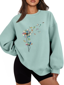 Detail of mint green sweatshirt featuring creative dandelion book print and ribbed collar