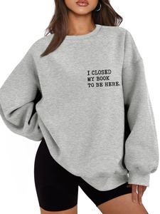 Detailed close-up of 'I CLOSED MY BOOK TO BE HERE' print on gray cotton sweatshirt