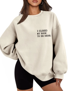 Close-up of 'I CLOSED MY BOOK TO BE HERE' print on beige crewneck sweatshirt for women