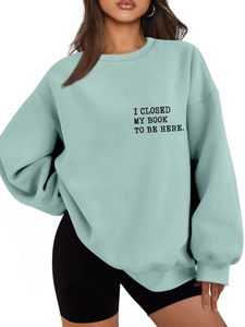 Detail of light green oversized sweatshirt showing the black text print on the chest