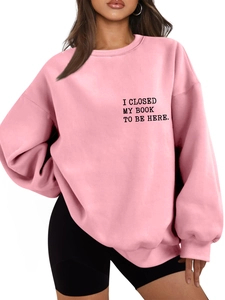 Close-up of pink oversized sweatshirt with I CLOSED MY BOOK TO BE HERE print on chest