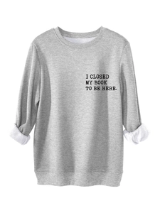 Detail of the slogan print I CLOSED MY BOOK TO BE HERE on a grey thick cotton sweatshirt