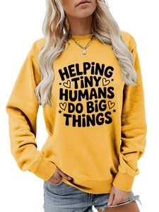 Detail of Helping Tiny Humans Do Big Things text print on yellow crewneck sweatshirt