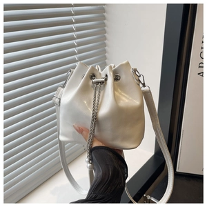 Detail showing the white drawstring bucket bag with silver chain and pearl charms
