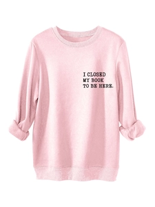 Close-up of pink crewneck sweatshirt featuring I CLOSED MY BOOK TO BE HERE text print
