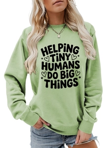 Detail of the light green sweatshirt featuring 'HELPING TINY HUMANS DO BIG THINGS' print