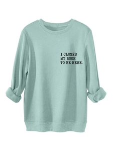 Detail of sage green sweatshirt showing ribbed cuffs and text print I Closed My Book