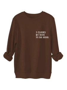Detail of white text print I CLOSED MY BOOK TO BE HERE on dark brown fleece sweatshirt