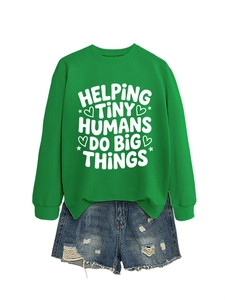 Flat lay of green sweatshirt with 'Helping Tiny Humans' text and ripped denim shorts