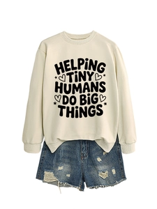Flat lay of cream sweatshirt with black printed text and distressed denim shorts